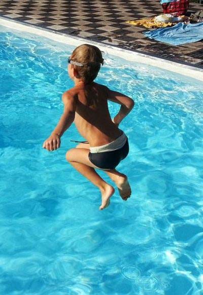 Young Boy Jumping Into Pool